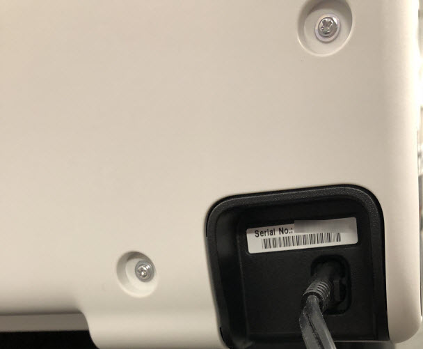 The serial number is on a white sticker above the power cord connector on the back of the printer